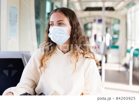 Portrait of a focused girl in a protective mask riding on public transport 84203925