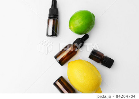 Essential oil bottles and citrus fruit on white background Essential oil bottles and citrus fruit on white background 84204704
