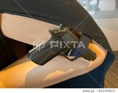 woman in black dress holding gun over grey woman in black dress holding gun over grey 84204823
