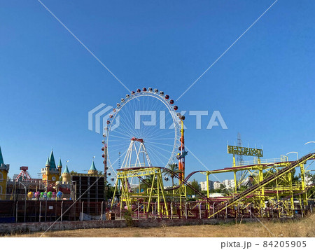 Ferris wheel and roller coaster rides at pier pacific park at sunset with people riding attractions 84205905