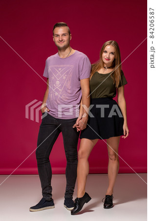 Totally in love. Full length of beautiful young couple embracing and smiling while standing against burgundy background Totally in love. Full length of beautiful young couple embracing and smiling while standing against burgundy background 84206587