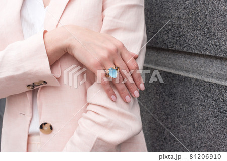 People, fashion, jewelry and luxury concept, closeup of woman wearing luxury jewelry standing on the street. Color gemstone ring and pendant with colored diamonds and gemstones People, fashion, jewelry and luxury concept, closeup of woman wearing luxury jewelry standing on the street. Color gemstone ring and pendant with colored diamonds and gemstones 84206910