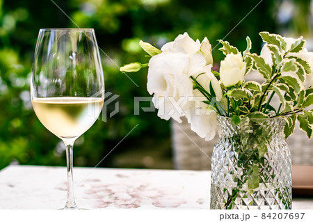 White wine in luxury restaurant on summer garden terrace, wine tasting experience at winery in the vineyard, gourmet tour and holiday travel White wine in luxury restaurant on summer garden terrace, wine tasting experience at winery in the vineyard, gourmet tour and holiday travel 84207697