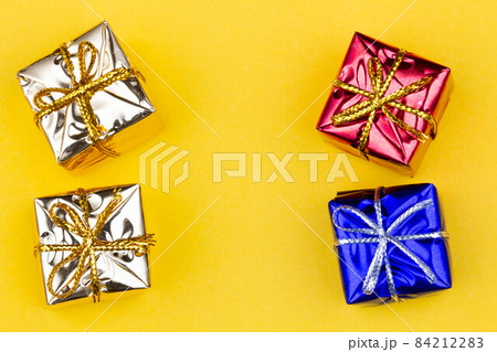 Box with gift on a yellow background with copy space for text. Golden, red, blue boxes with gifts. Christmas gift boxes. Holidays Gifting. New Year gift boxes to family woman, man. Top view. Close-up 84212283