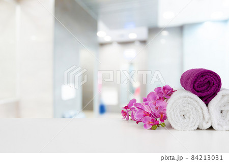 Towels with flowers on light table against blurred background 84213031