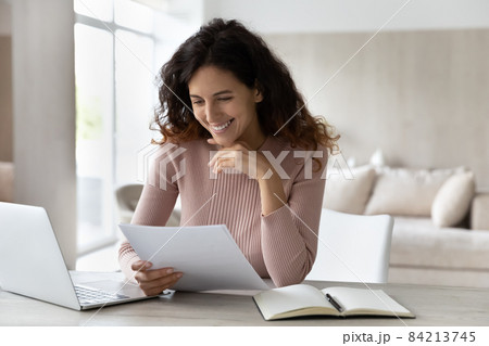 Happy businesswoman reading good news in letter, sitting at desk 84213745