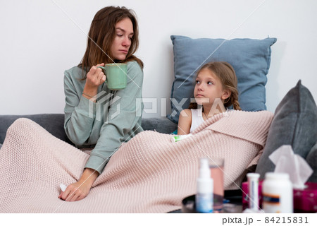 Mother and daughter catching colds together, sit on the couch and heal. Mother and daughter catching colds together, sit on the couch and heal. 84215831
