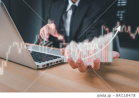 Businessman hand holding holographic graphs and stock market statistics gain profits on office desk, Business growth, progress or success concept. 84218478
