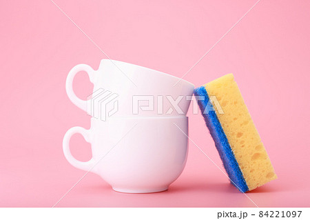 Creative, minimal dishwashing concept, yellow cleaning sponge next to two white ceramic cups on pink background Creative, minimal dishwashing concept, yellow cleaning sponge next to two white ceramic cups on pink background 84221097