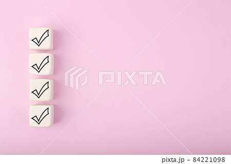 Four black checkmarks on white toy cubes in a row against bright pastel purple background with copy space Four black checkmarks on white toy cubes in a row against bright pastel purple background with copy space 84221098