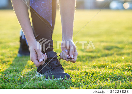 Close-up of female hands tying shoelace on running shoes before practice. Runner getting ready for training. Sport active lifestyle concept. Close-up of female hands tying shoelace on running shoes before practice. Runner getting ready for training. Sport active lifestyle concept. 84223828