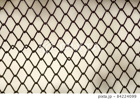 Background and texture for design. Abstract chain link fence texture against grungy gray color wall. 84224099