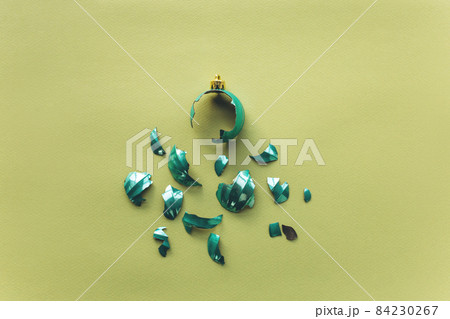 Broken Christmas tree toy ball on a green background in a minimal style. The concept of an unsuccessful new year celebration Broken Christmas tree toy ball on a green background in a minimal style. The concept of an unsuccessful new year celebration 84230267