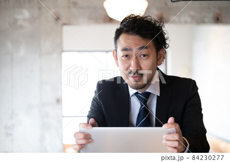 問題が起こってパソコンを抱えこむ管理職風の日本人男性　カメラ目線　コピースペースあり 84230277