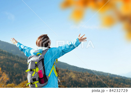 バナーに使いやすい【秋】の登山やトレッキングを楽しむ女性 頂上で手を広げる コピースペースあり ※春 84232729