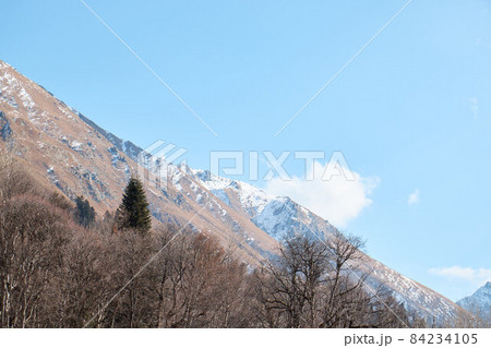 Landscape in the mountains, river and coniferous forest, autumn, the first snow on the slopes, fallen trees and shrubs 84234105