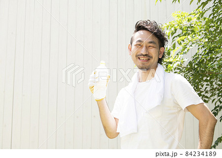 熱中症にならないよう、猛暑の屋外の仕事で水分補給をするヒゲの生えたカメラ目線の爽やかな笑顔の男性 熱中症にならないよう、猛暑の屋外の仕事で水分補給をするヒゲの生えたカメラ目線の爽やかな笑顔の男性 84234189