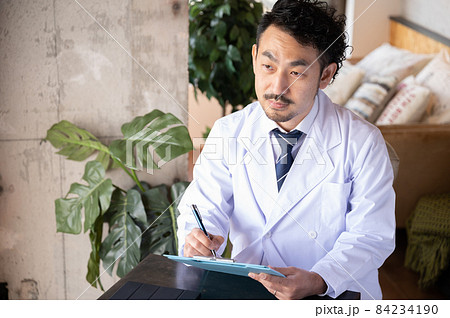 患者さんの目を見て話をカウンセリングしながらカルテを記入する日本人ドクター1 84234190