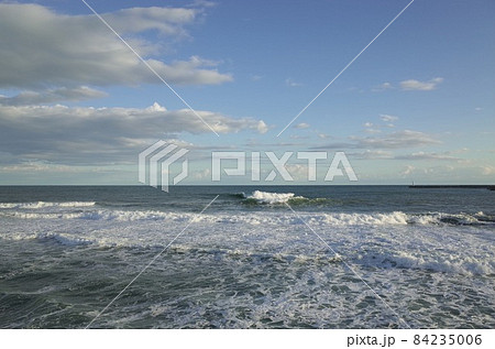 初冬の小春日和の午後の青い空と薄暗い雲と少し荒れた海 84235006