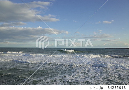 初冬の小春日和の午後の青い空と薄暗い雲と少し荒れた海 84235018