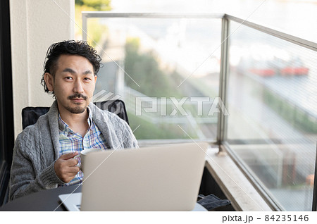ベランダでくつろぎながら仕事をする日本人男性 ベランダでくつろぎながら仕事をする日本人男性 84235146
