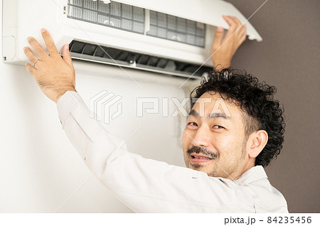 エアコンを掃除する笑顔のハウスクリーニングのイメージ コピースペースあり エアコンを掃除する笑顔のハウスクリーニングのイメージ コピースペースあり 84235456