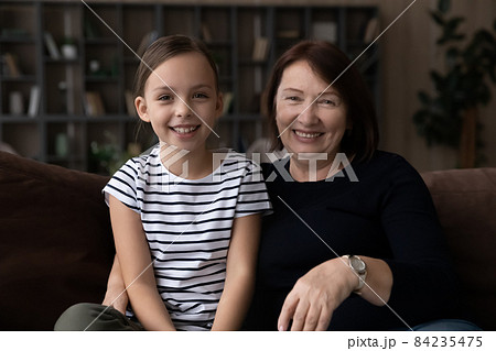 Head shot portrait smiling grandmother with granddaughter making video call Head shot portrait smiling grandmother with granddaughter making video call 84235475