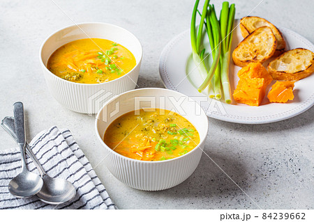 Homemade broccoli cheddar cheese soup with green onions in white bowl, gray background. Vegetarian food concept. 84239662