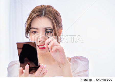 メイクする若い女性　ビューラー 84240355