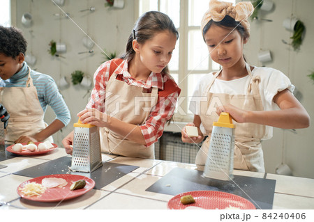 Little girl looking at the plate of her friend during cooking lesson in the kitchen 84240406