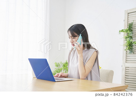 パソコンを見て電話する女性 リビング パソコンを見て電話する女性 リビング 84242376