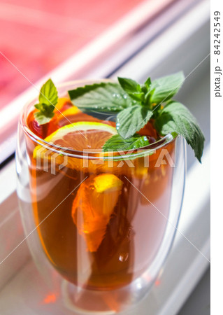 Black and green tea with lemon, cinnamon sticks and mint leaves. Hot drink. Healthy melissa tea natural organic aromatic drink in cup. Summer, Autumn winter warming drink. 84242549