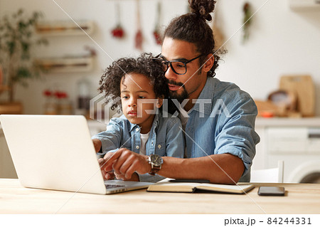 Young african american dad helping schoolboy son with homework on laptop during distant education Young african american dad helping schoolboy son with homework on laptop during distant education 84244331