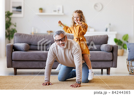 Cute little girl granddaughter playing and having fun with active positive grandfather at home 84244365