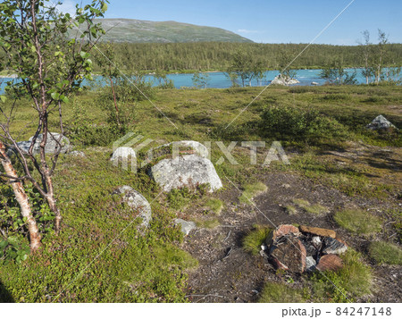 Beatiful camping spot in northern landscape in Swedish Lapland with turquoise blue Vuojatadno river, birch tree forest and green mountains at Padjelantaleden hiking trail. Summer sunny day, blue sky Beatiful camping spot in northern landscape in Swedish Lapland with turquoise blue Vuojatadno river, birch tree forest and green mountains at Padjelantaleden hiking trail. Summer sunny day, blue sky 84247148