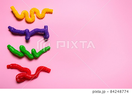 Colorful antistress pop tube toys on pink paper with large copy space Colorful antistress pop tube toys on pink paper with large copy space 84248774