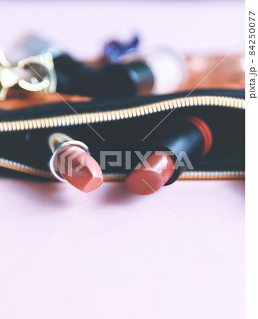 Bright composition of fashion accessories. Glitter sequins cosmetic bag with nail polishes, lipsticks, hair pins. Objects on soft pastel background. Flat lay, top view. 84250077