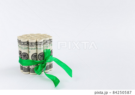 100 dollar bills in rolls tied with green ribbon. Money gift. 84250587