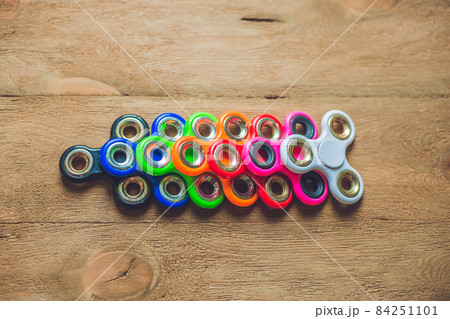 Colored fidget spinners stress relieving toy on wooden background Colored fidget spinners stress relieving toy on wooden background 84251101