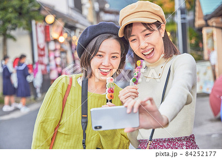 湯布院で食べ歩きをする若い女性と友達 84252177