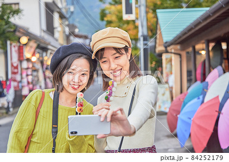 湯布院で食べ歩きをする若い女性と友達 84252179