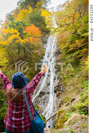 紅葉の滝にマイナスイオンをもらうミドル女性 84253289