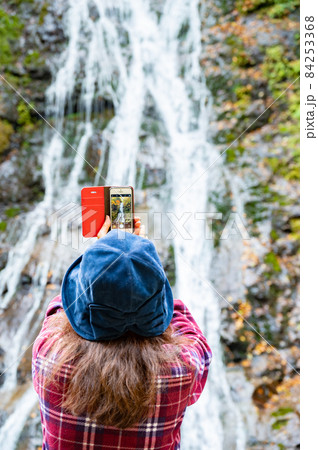 紅葉の滝をスマホで写真を撮るミドル女性 紅葉の滝をスマホで写真を撮るミドル女性 84253368