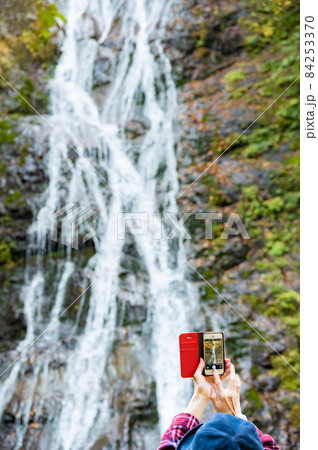 紅葉の滝をスマホで写真を撮るミドル女性 紅葉の滝をスマホで写真を撮るミドル女性 84253370