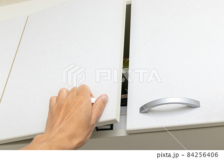 高い位置にあるキャビネットの取っ手に手を掛ける 84256406