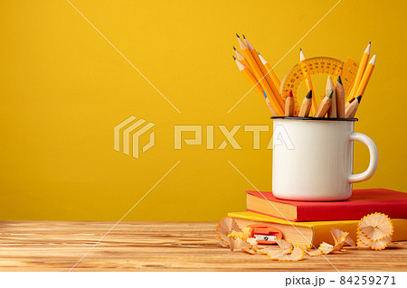 Metal cup with sharp pencils and pencil shavings on wooden desk Metal cup with sharp pencils and pencil shavings on wooden desk 84259271