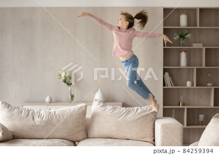 Cute little girl child having fun, jumping high on couch 84259394