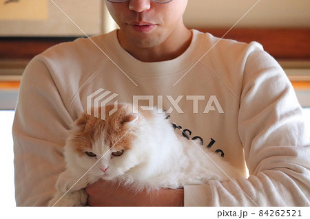下を見て不安な人と猫 抱っこする飼い主 束縛の写真素材