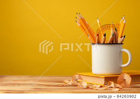 Metal cup with sharp pencils and pencil shavings on wooden desk 84263902