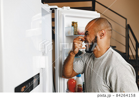 African american man closing nose because of bad smell from fridge 84264158